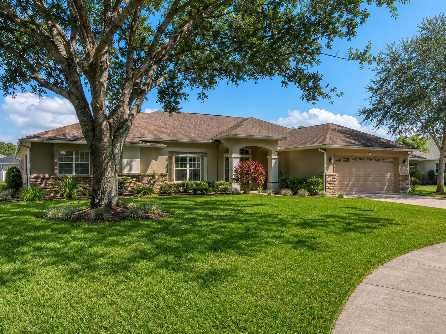 Maintained Florida home and residential lawn beneath a mature shade tree